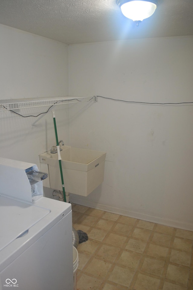 laundry area with sink, a textured ceiling, and washer / dryer