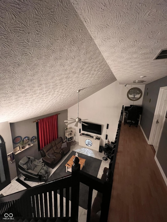 interior space with a textured ceiling, ceiling fan, hardwood / wood-style floors, and lofted ceiling