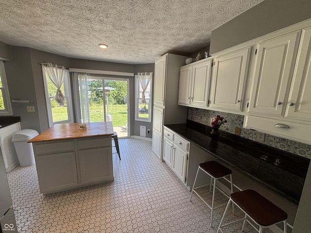 11720 Grenadier Ln, Indianapolis, IN 46229 - kitchen featuring wood counters, white cabinets, a textured ceiling, and baseboards