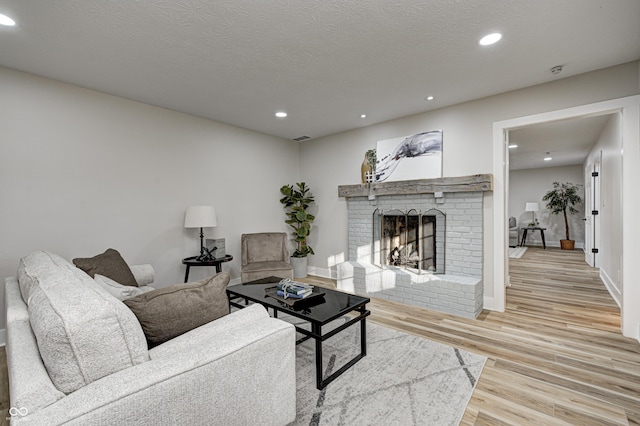 living room featuring a textured ceiling, a fireplace, and light hardwood / wood-style flooring