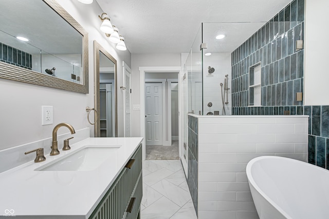 bathroom with tile walls, vanity, independent shower and bath, and a textured ceiling