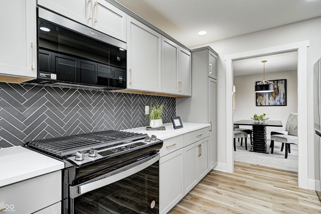 kitchen featuring gas stove, gray cabinetry, backsplash, light hardwood / wood-style floors, and decorative light fixtures