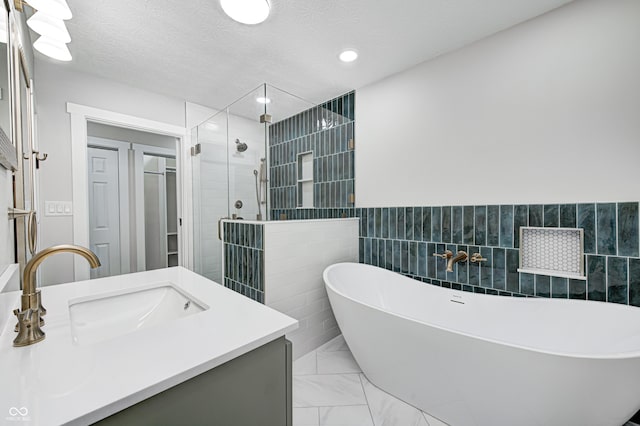 bathroom featuring a textured ceiling, vanity, tile walls, and independent shower and bath