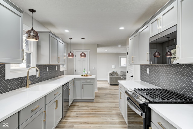 kitchen with gray cabinets, sink, decorative light fixtures, and appliances with stainless steel finishes