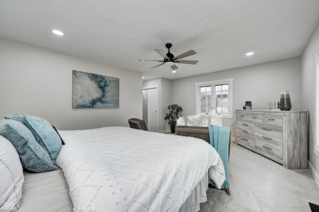 carpeted bedroom featuring a textured ceiling, a closet, and ceiling fan