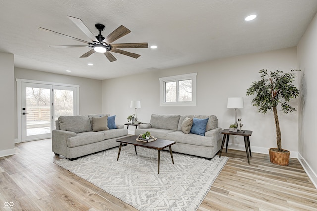 living room with ceiling fan, light hardwood / wood-style floors, and a textured ceiling