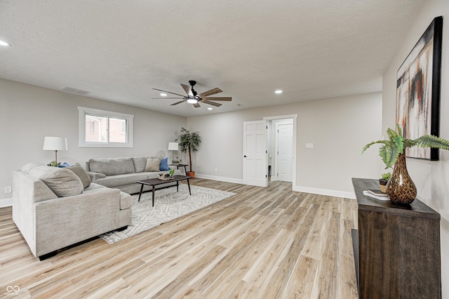 living room with ceiling fan, light hardwood / wood-style floors, and a textured ceiling