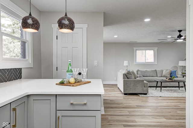 kitchen with gray cabinetry, hanging light fixtures, and a wealth of natural light