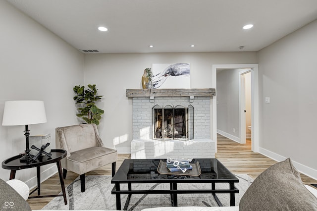 living room with a brick fireplace and light wood-type flooring