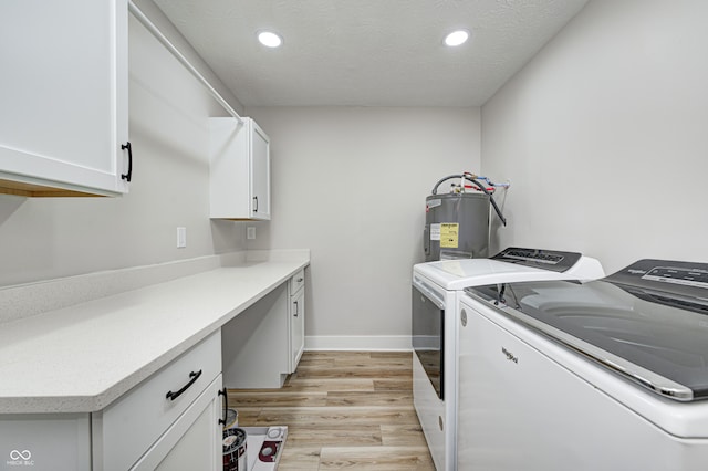 laundry room with cabinets, light wood-type flooring, a textured ceiling, water heater, and separate washer and dryer