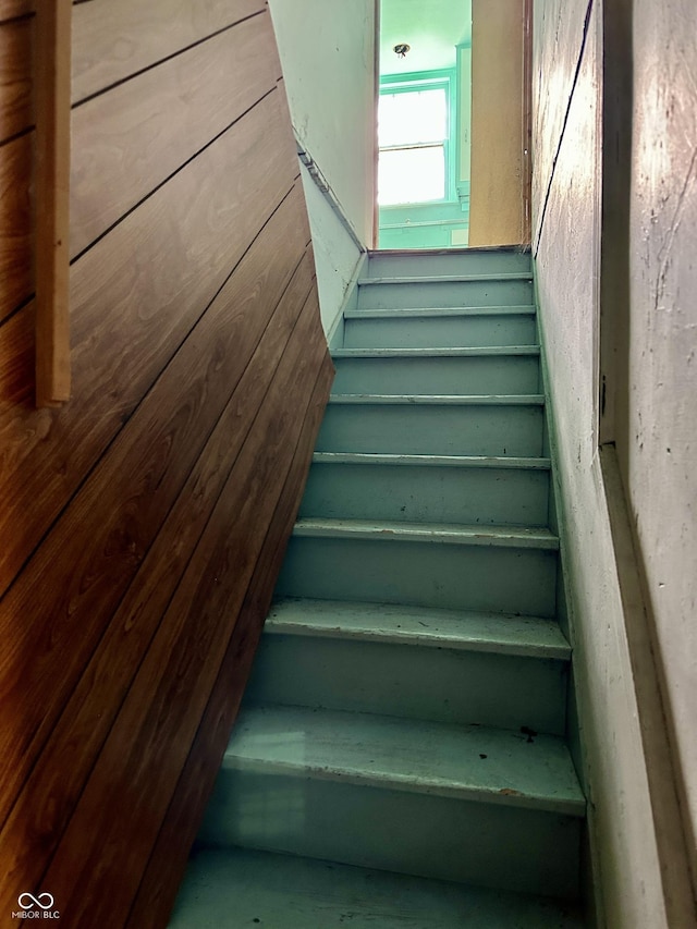 stairway featuring wood walls