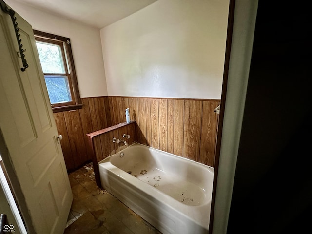 bathroom featuring tile patterned floors, wood walls, and a washtub