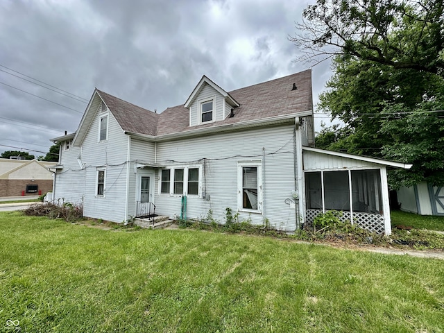 rear view of house featuring a sunroom and a lawn