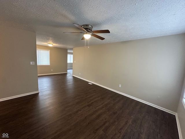 empty room featuring a textured ceiling, ceiling fan, and dark wood-type flooring