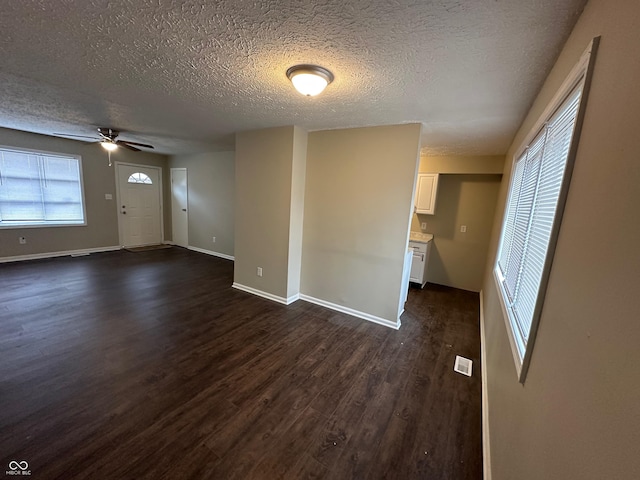 unfurnished living room with ceiling fan, dark hardwood / wood-style flooring, and a textured ceiling