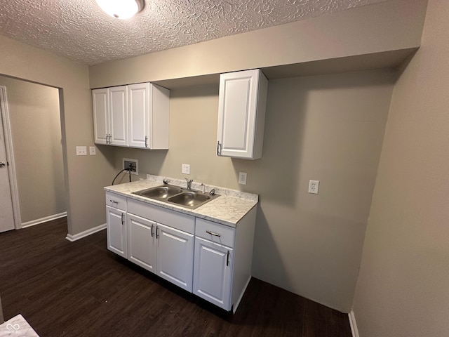 kitchen with dark hardwood / wood-style flooring, white cabinetry, sink, and a textured ceiling