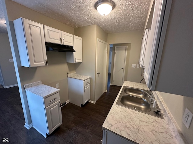 kitchen featuring white cabinets, dark hardwood / wood-style flooring, a textured ceiling, and sink