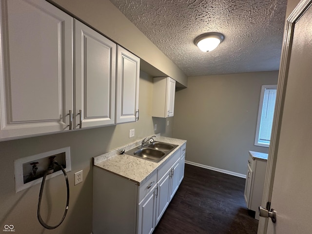 laundry room with sink, cabinets, dark hardwood / wood-style floors, hookup for a washing machine, and a textured ceiling