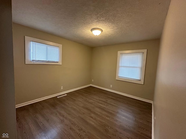 unfurnished room featuring a textured ceiling and dark wood-type flooring