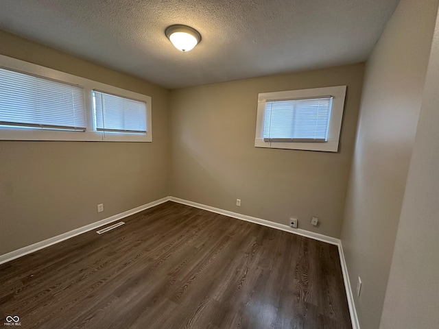 unfurnished room with dark hardwood / wood-style flooring and a textured ceiling