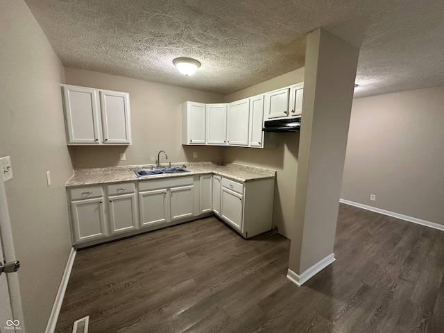 kitchen with a textured ceiling, sink, white cabinets, and dark hardwood / wood-style floors