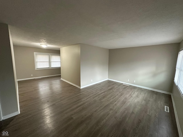 empty room featuring a textured ceiling and dark wood-type flooring