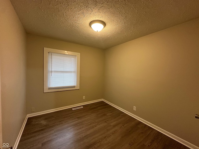 empty room with a textured ceiling and dark wood-type flooring