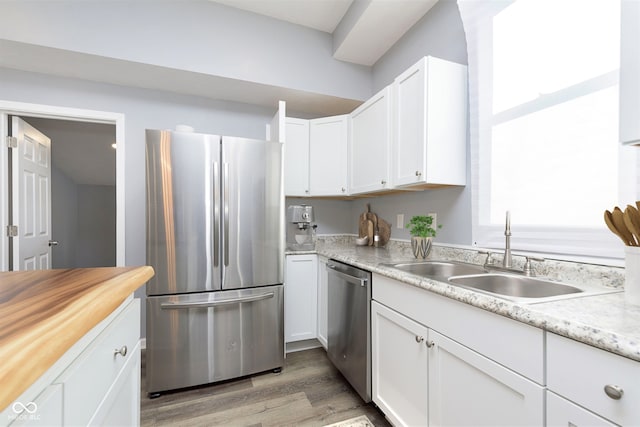 kitchen with sink, white cabinets, stainless steel appliances, and light hardwood / wood-style flooring