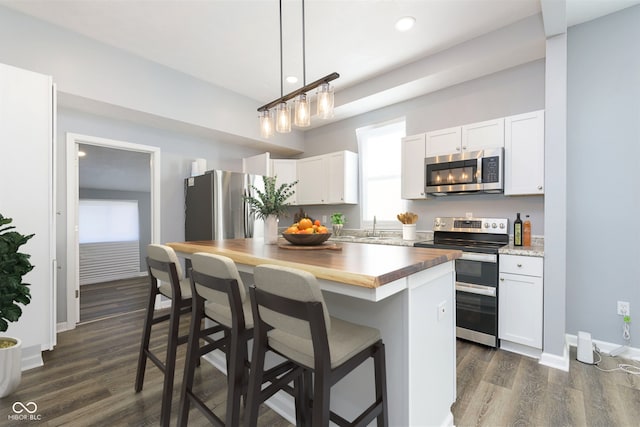 kitchen featuring stainless steel appliances, white cabinets, dark hardwood / wood-style floors, a kitchen island, and butcher block counters