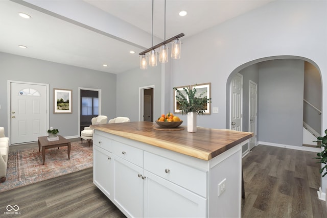 kitchen with wood counters, dark wood-type flooring, a center island, white cabinetry, and hanging light fixtures