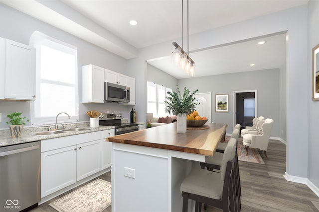 kitchen with stainless steel appliances, white cabinetry, a wealth of natural light, and sink