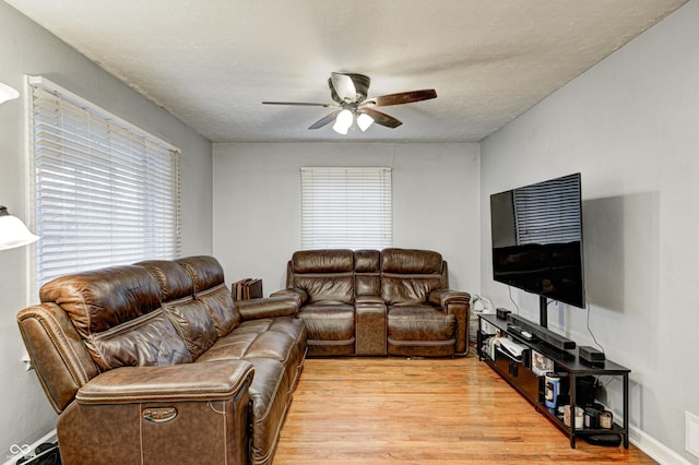 living room with a textured ceiling, light hardwood / wood-style floors, and ceiling fan