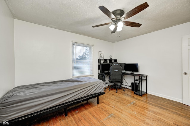 bedroom featuring ceiling fan, wood-type flooring, and a textured ceiling