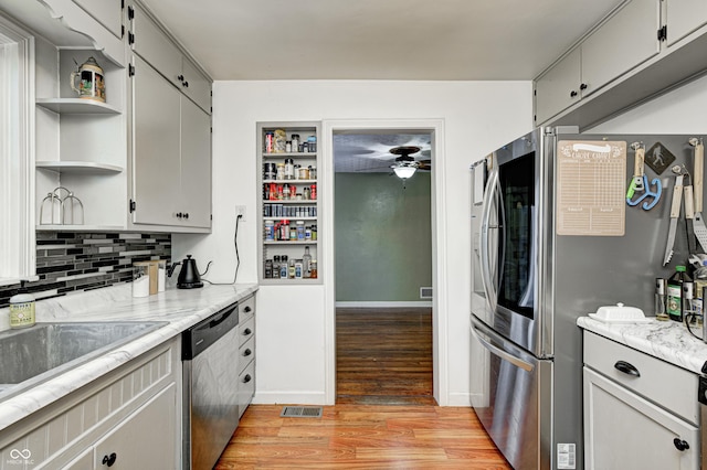 kitchen with ceiling fan, sink, stainless steel appliances, tasteful backsplash, and light wood-type flooring