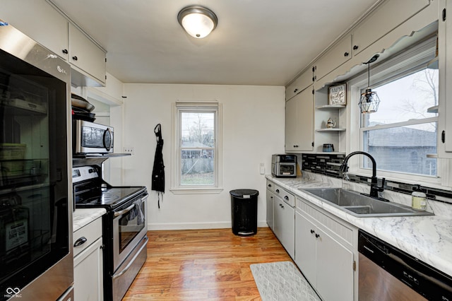 kitchen featuring white cabinets, stainless steel appliances, hanging light fixtures, and sink