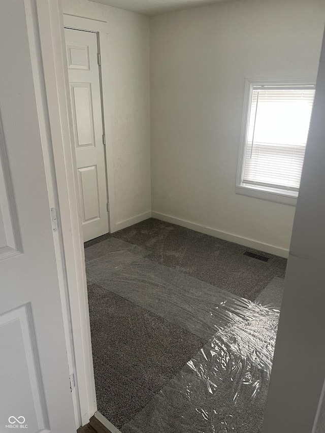 spare room featuring dark colored carpet