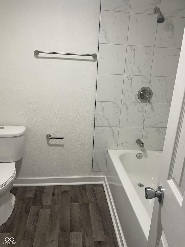 bathroom featuring hardwood / wood-style floors, tiled shower / bath combo, and toilet