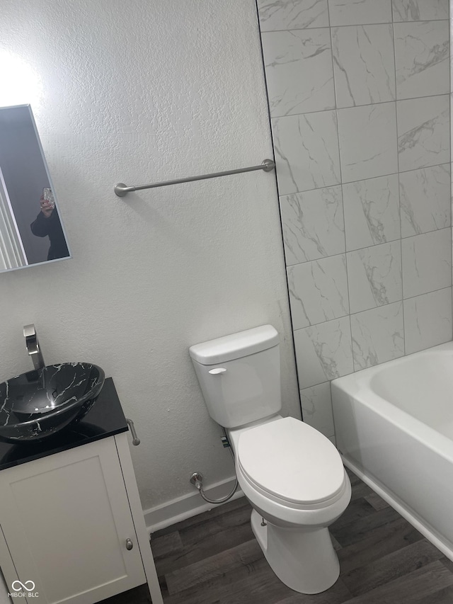 full bathroom with vanity, toilet, wood-type flooring, and tiled shower / bath