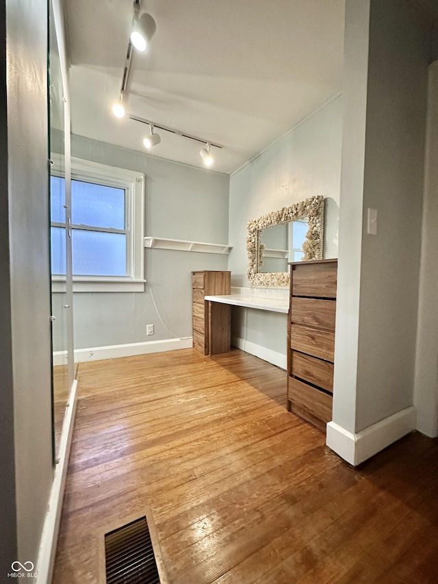 unfurnished bedroom featuring baseboards, built in desk, visible vents, and wood-type flooring