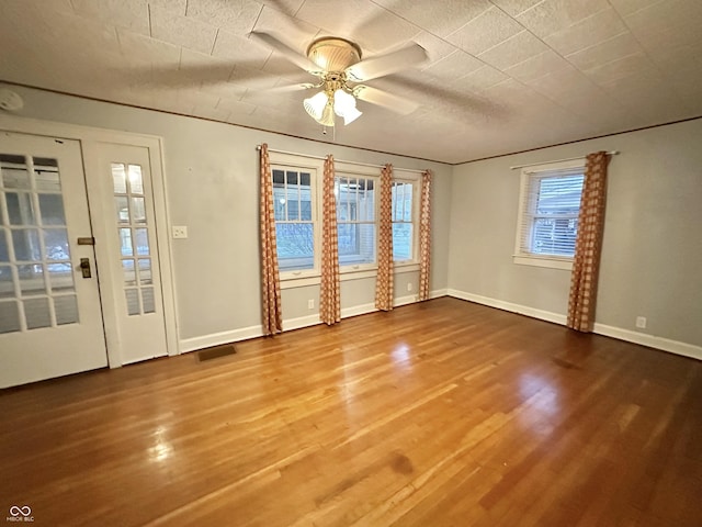 interior space featuring baseboards, visible vents, wood finished floors, and a ceiling fan