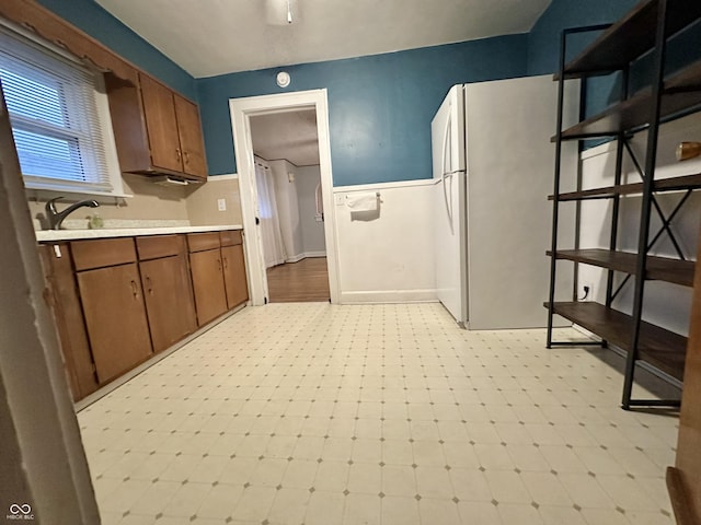 kitchen with light countertops, brown cabinets, freestanding refrigerator, and light floors