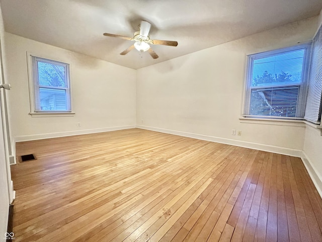 unfurnished room with baseboards, ceiling fan, visible vents, and wood-type flooring