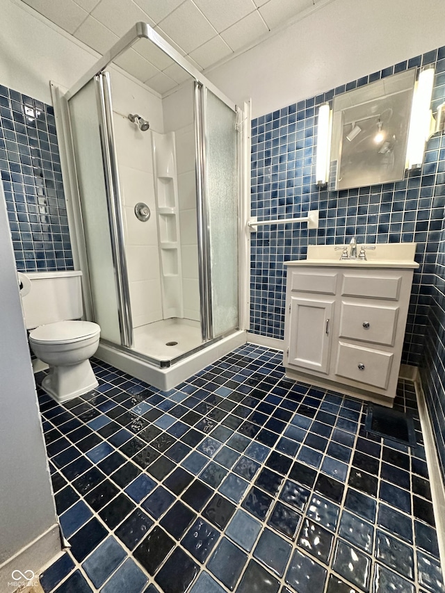 full bath featuring toilet, vanity, tile walls, and a shower stall