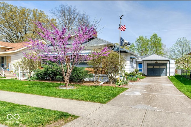 view of front of house featuring a front lawn, driveway, an outbuilding, and fence