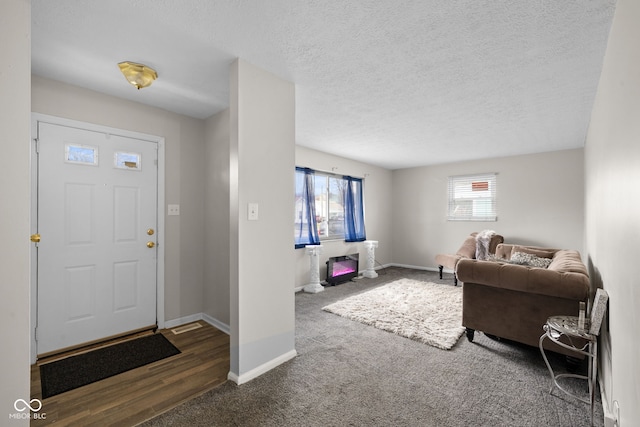 entryway with dark colored carpet, a wealth of natural light, and a textured ceiling