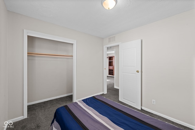 unfurnished bedroom with dark colored carpet, a textured ceiling, and a closet