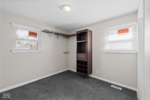 walk in closet with dark carpet