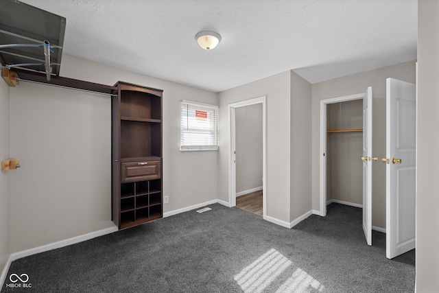 unfurnished bedroom featuring a closet, a textured ceiling, and dark colored carpet