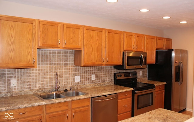 kitchen featuring backsplash, light stone counters, sink, and appliances with stainless steel finishes