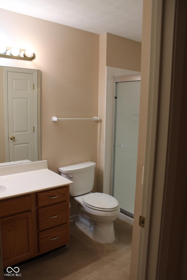 bathroom with vanity, toilet, an enclosed shower, and a textured ceiling